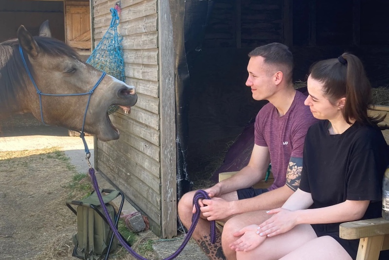 a young man and a young woman spending time with a horse for equine therapy